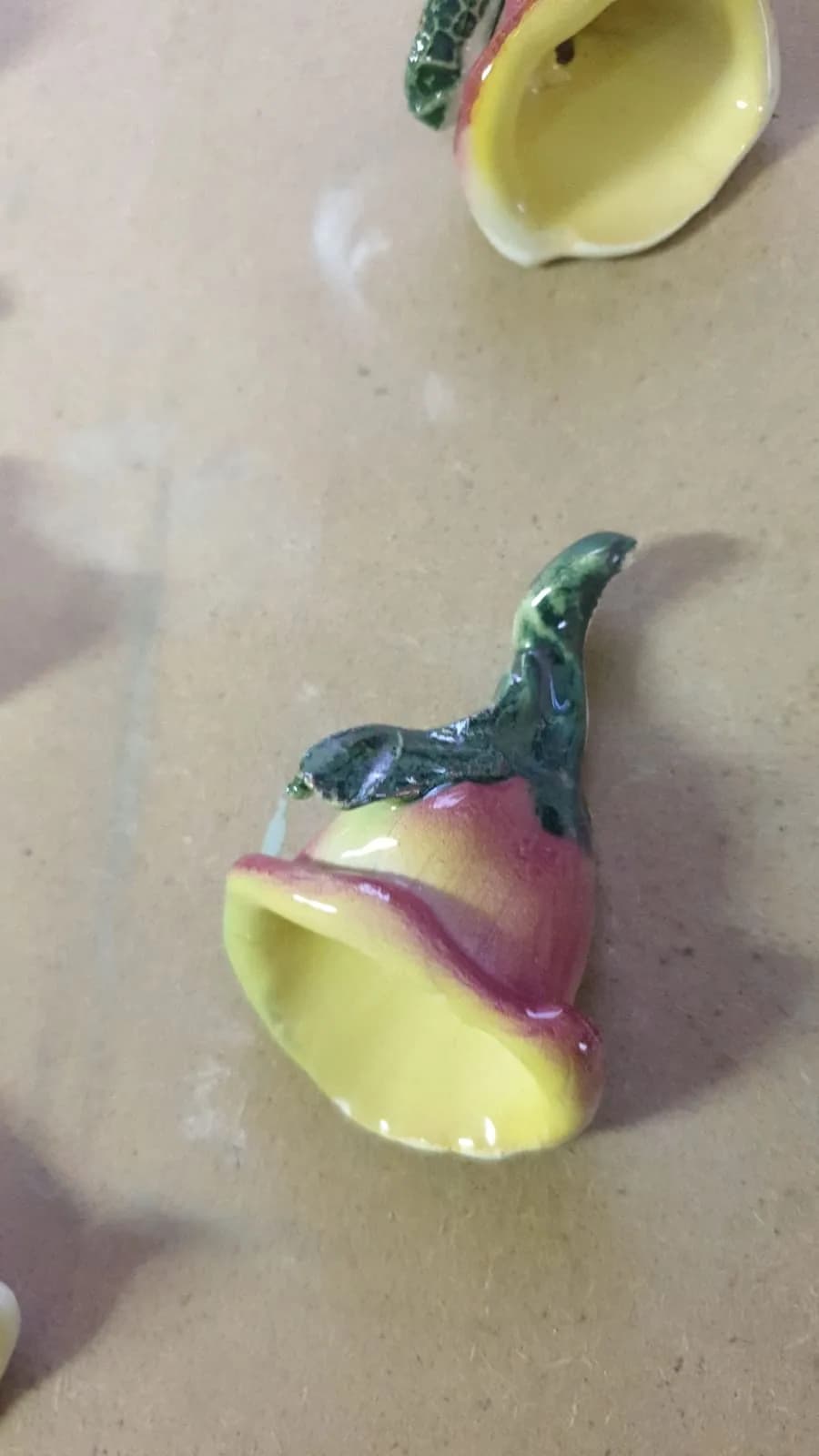 Una campanella smaltata in giallo e rosa, con il gambo verde a forma di foglia.