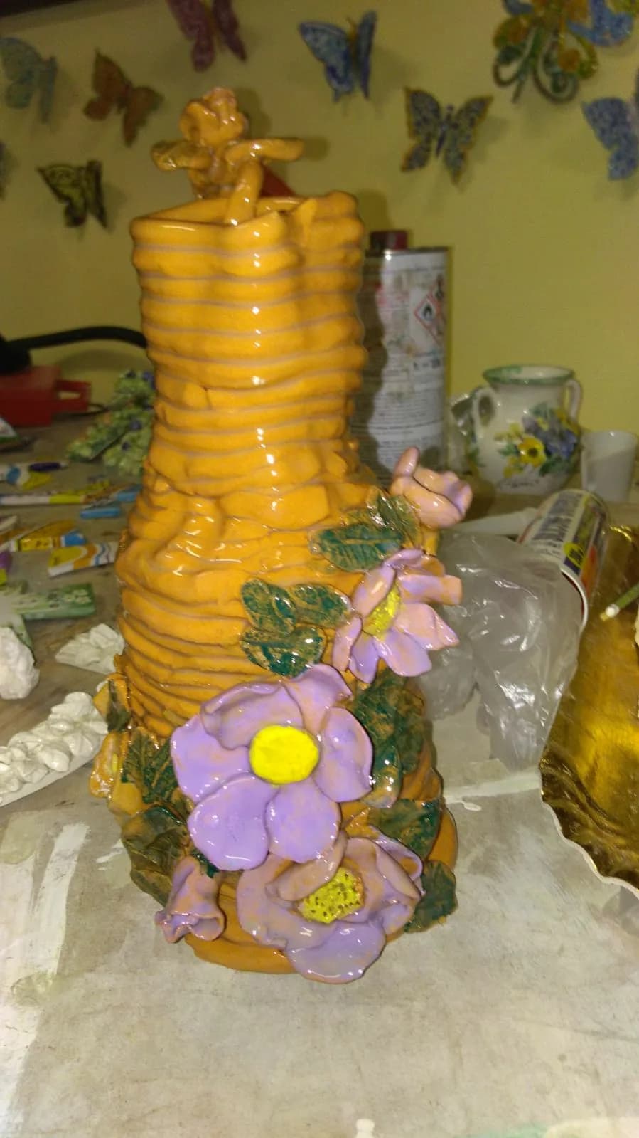 Un vaso giallo smaltato con fiori a rilievo, fatto da un'allieva.