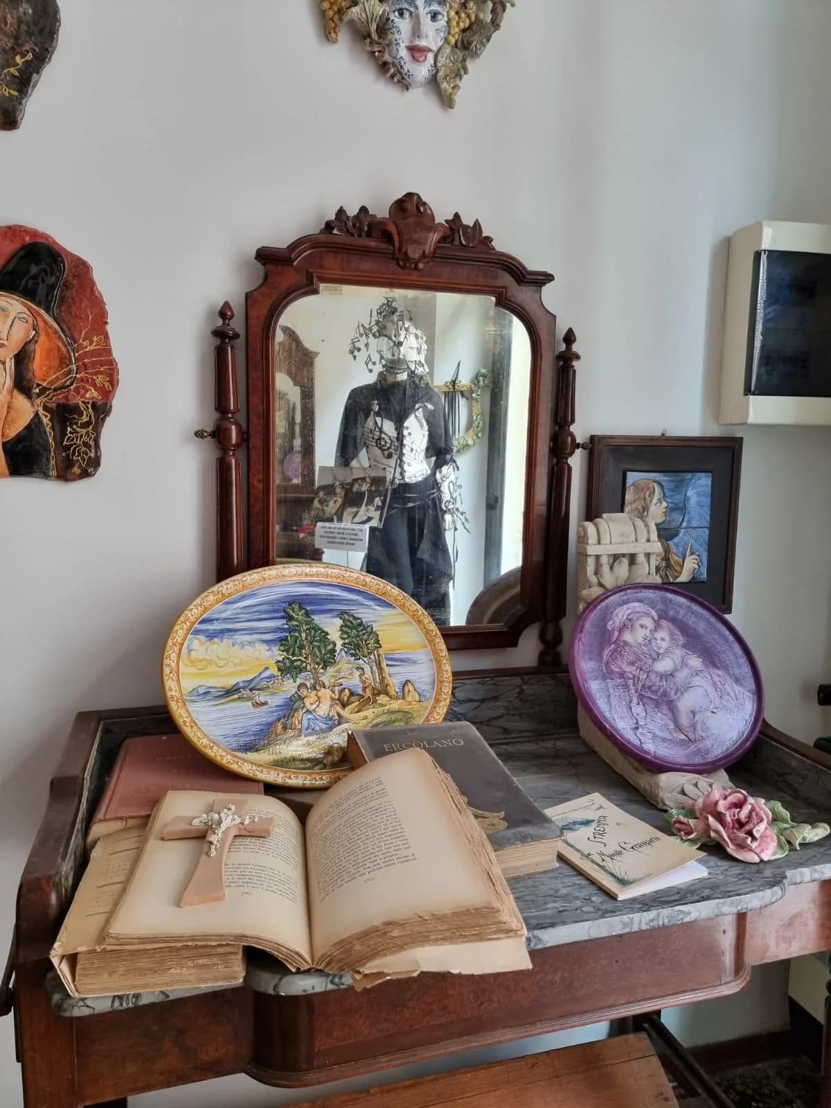 La consolle dell'atelier, con lo specchio antico e due piatti appoggiati.