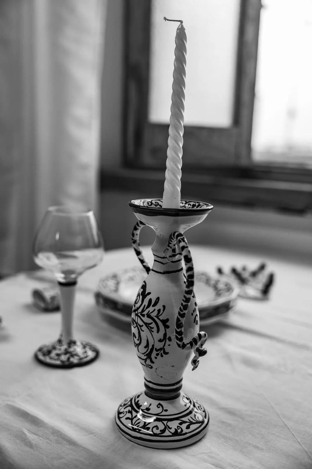 Un candeliere di ceramica e un calice, sulla tovaglia.