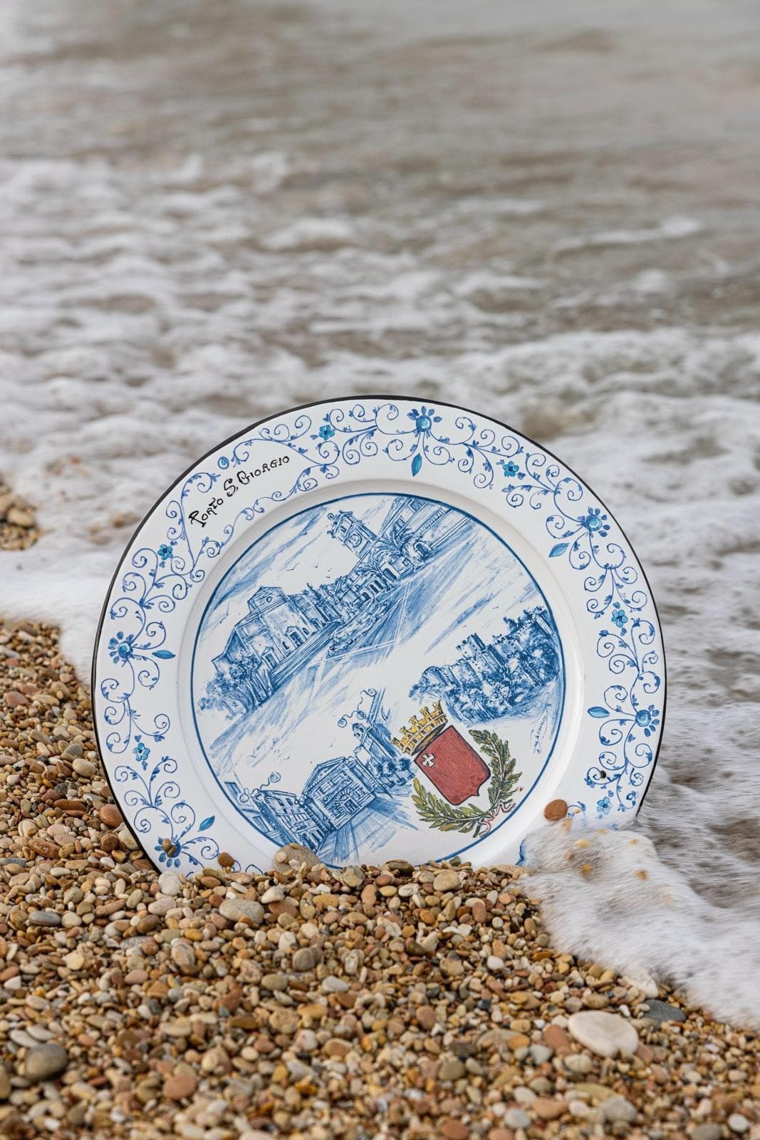 Maiolica plate reached by the foam of the wave as it retreats over the gravel.