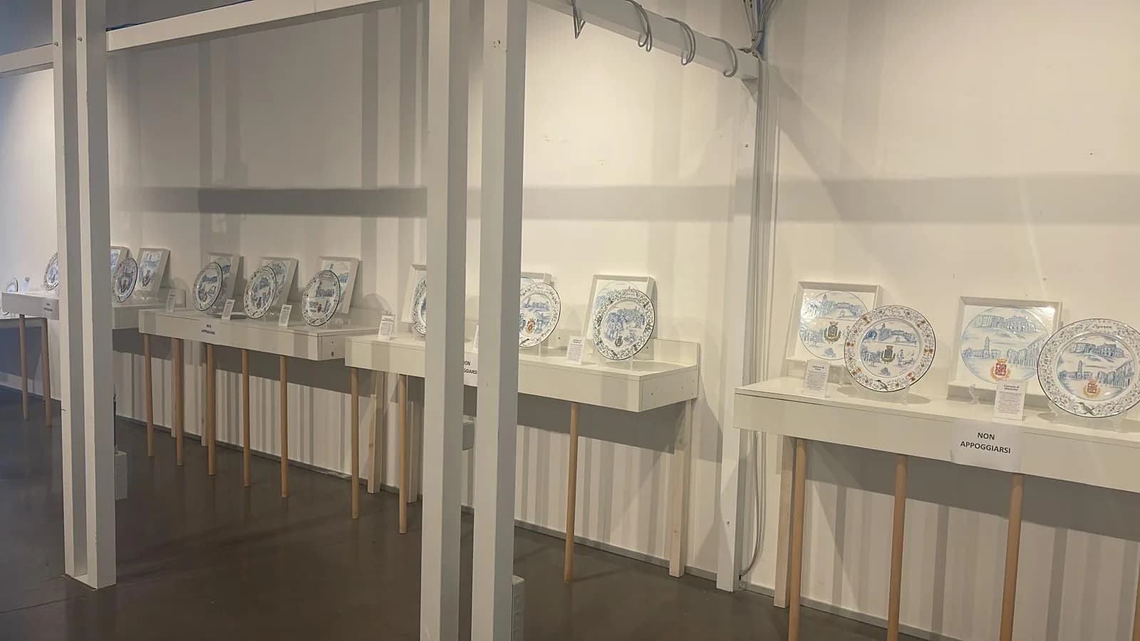 La sala della mostra con le nicchie alle pareti e i piatti in fila.
