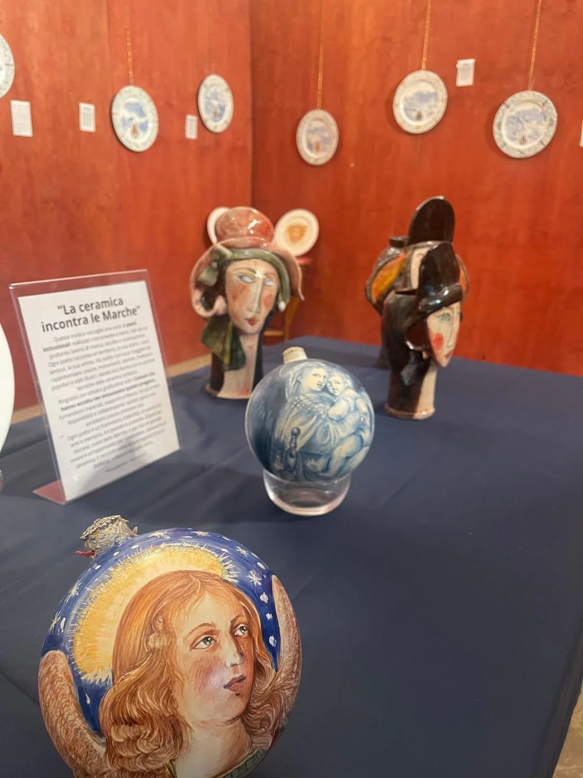 Teste di ceramica dipinte a mano, esposte sul tavolo blu.