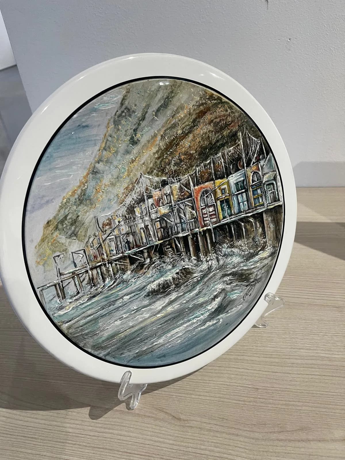 Un grande piatto con il porto e i pescatori, su cavalletto.