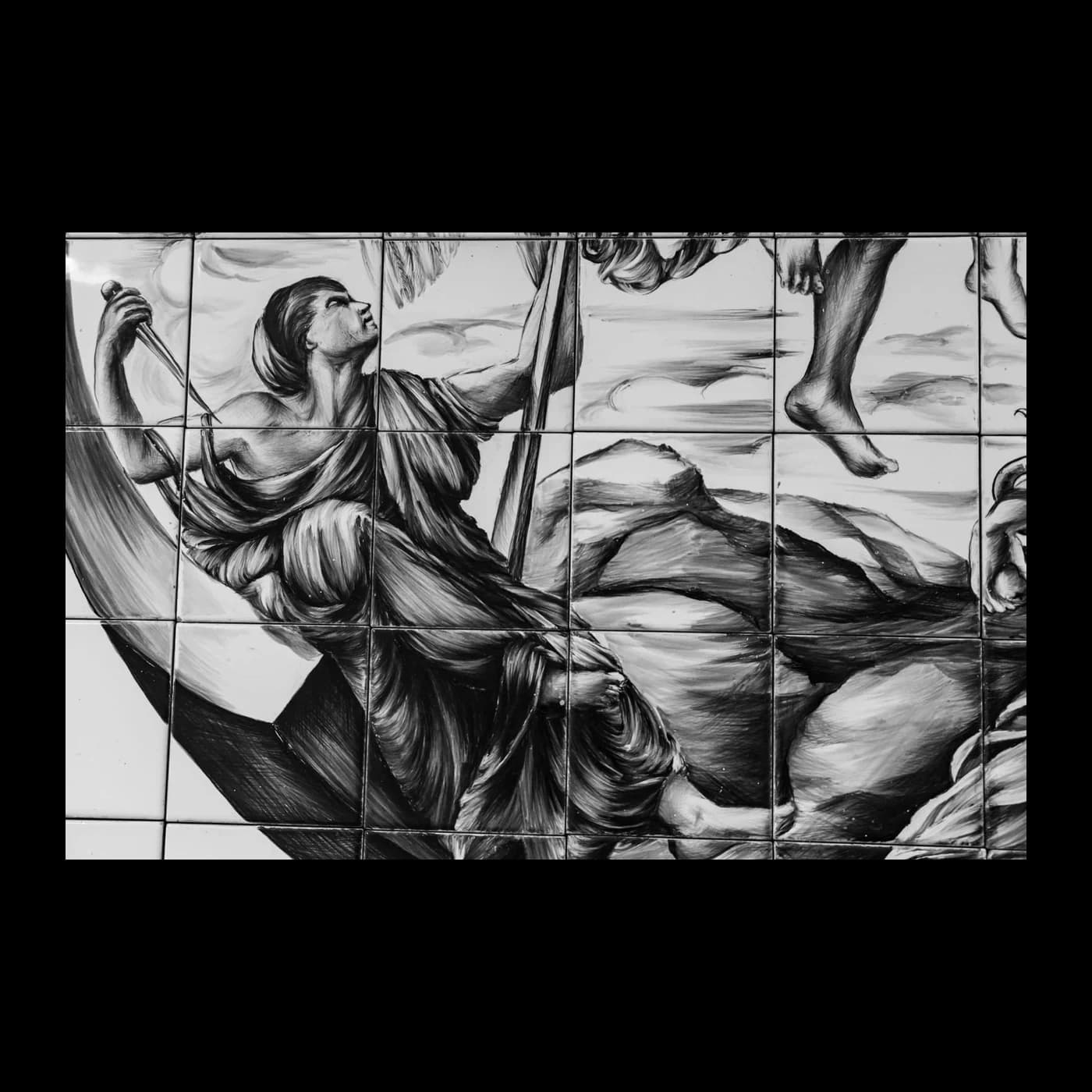Secondo pannello di piastrelle dipinto in monocromo, con una figura maschile che regge un'asta e altre figure sullo sfondo.