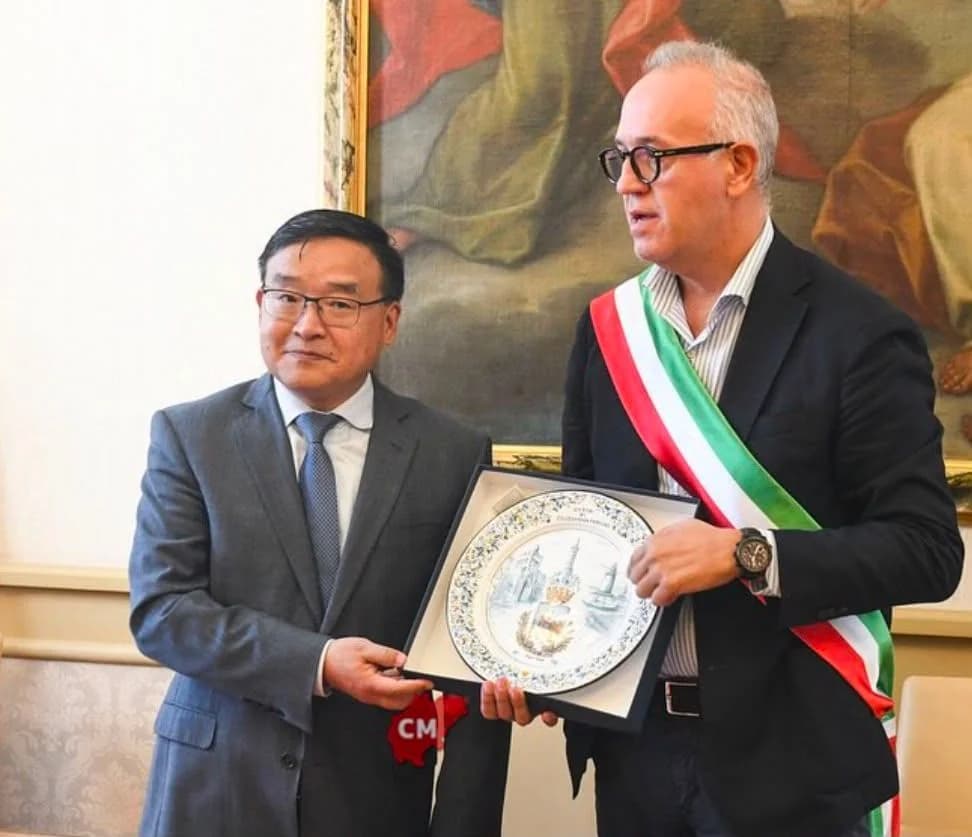 In una sala istituzionale, un ospite riceve il piatto incorniciato.
