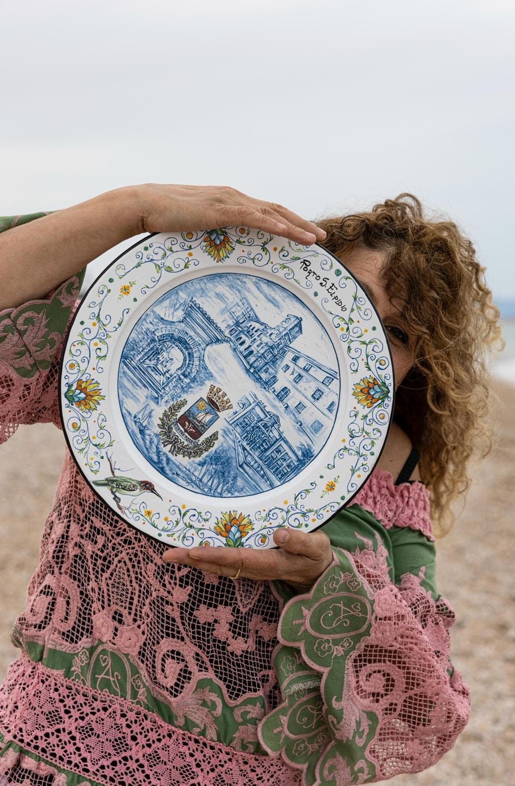 Paola Iannucci holds a maiolica plate against her chest, wrapped in a shawl.