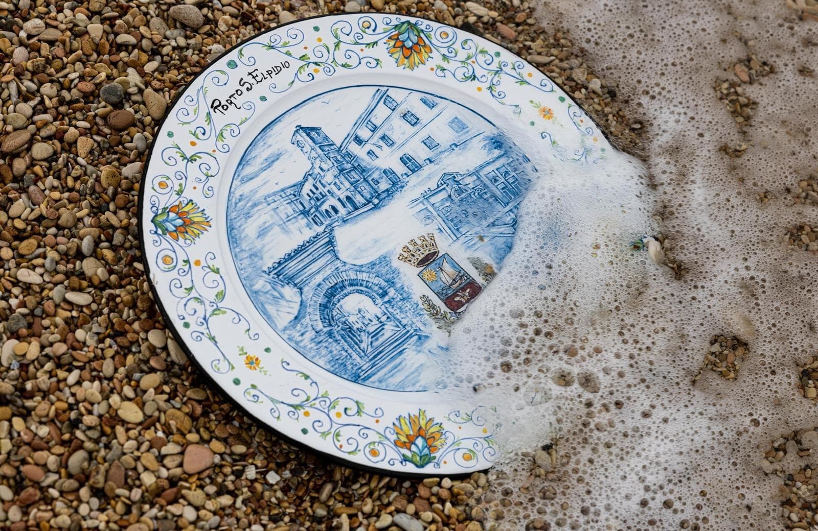 Piatto in maiolica dedicato a Porto Sant'Elpidio, sulla ghiaia, mezzo coperto dalla schiuma dell'onda che si ritira.